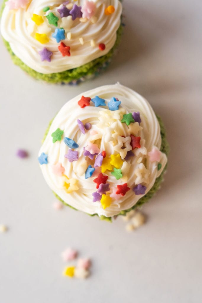 White frosting on cupcake with colorful rainbow star sprinkles