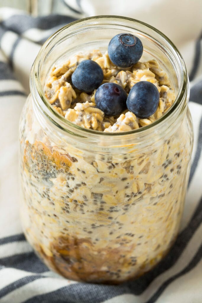 closeup of cookie dough overnight oats in mason jar with blueberries on top.