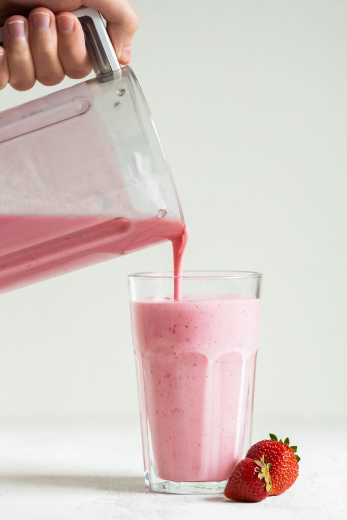 strawberry smoothie being poured into glass.