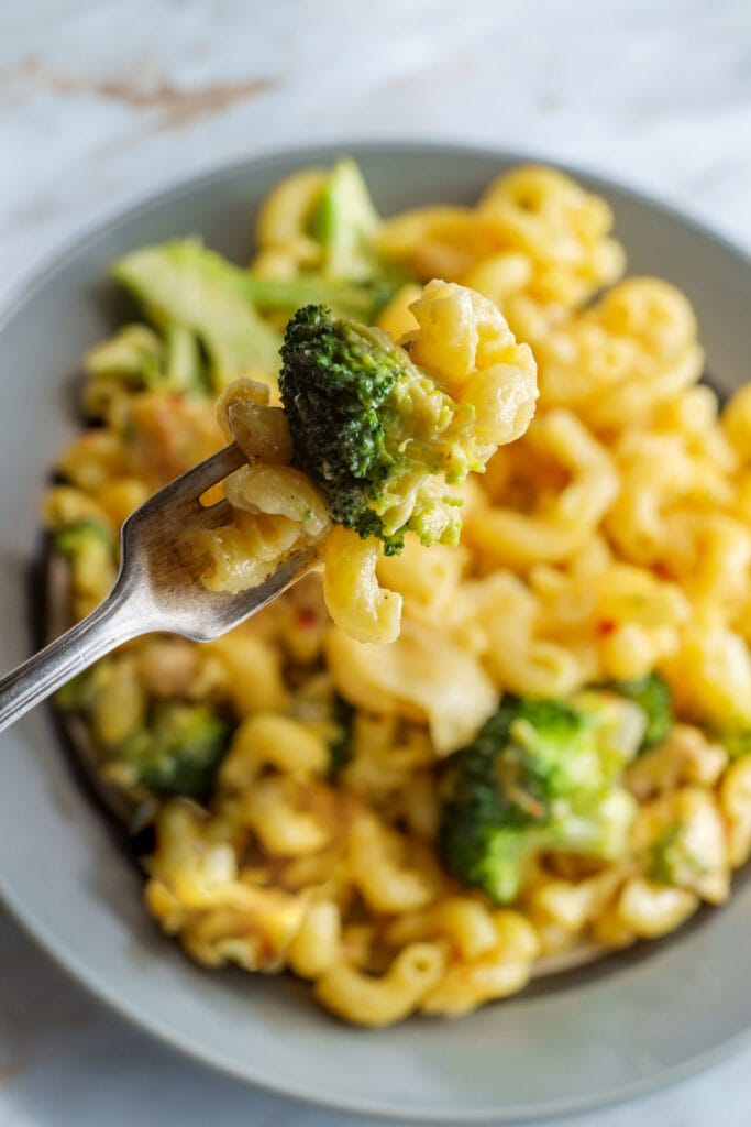 fork holding baked broccoli mac and cheese.