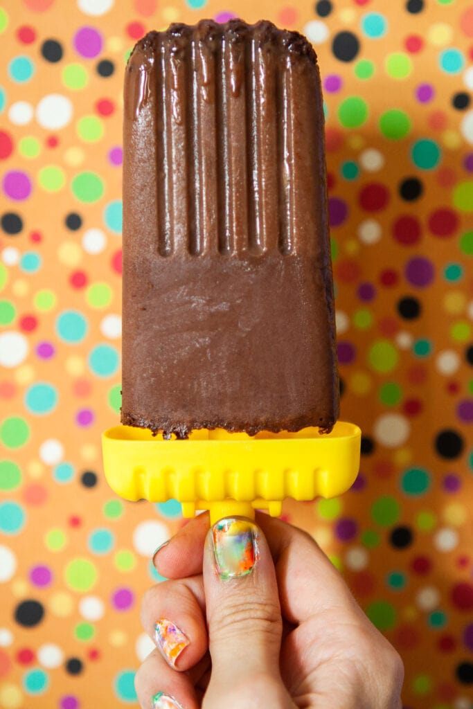 hand holding chocolate popsicle up.