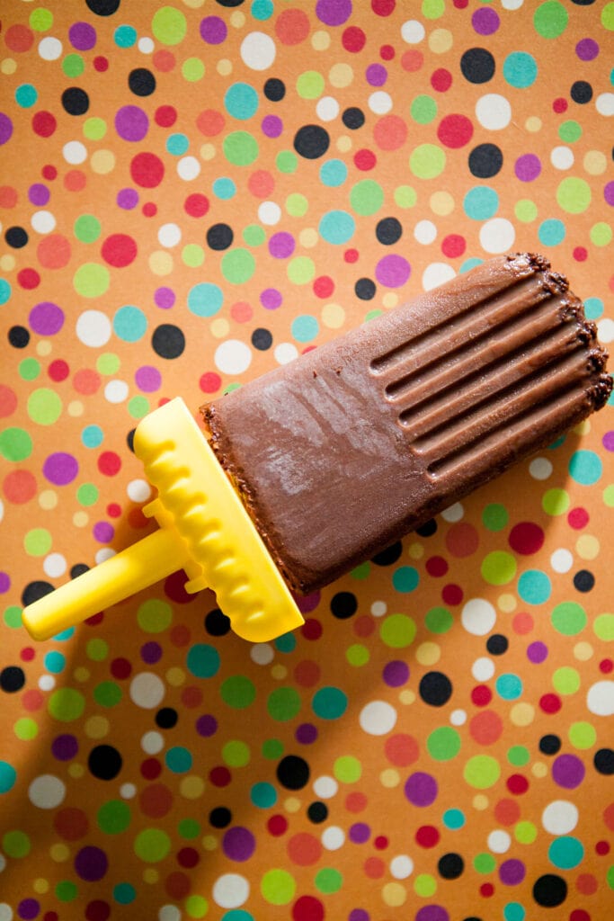 nutella chocolate popsicle laying on polka dot background.
