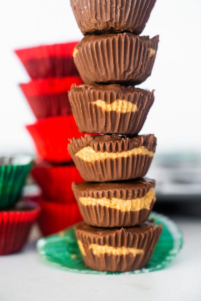 stack of homemade peanut butter cups on table in front of red and green muffin cups