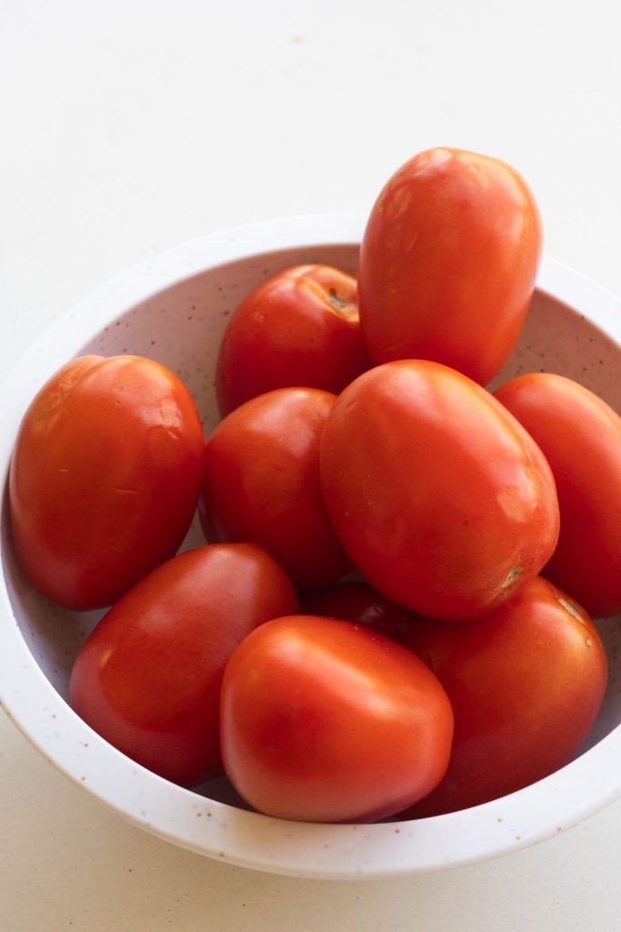 roma tomatoes in white bowl on table.