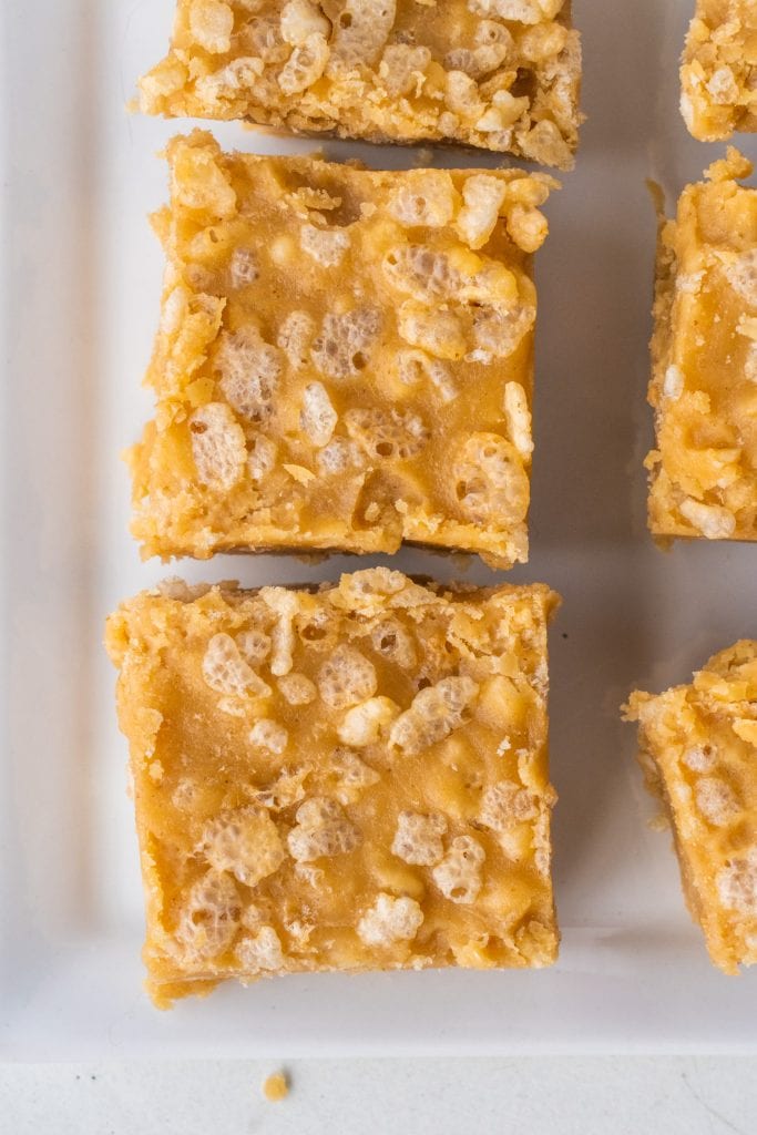 crispy peanut butter fudge squares on white plate.