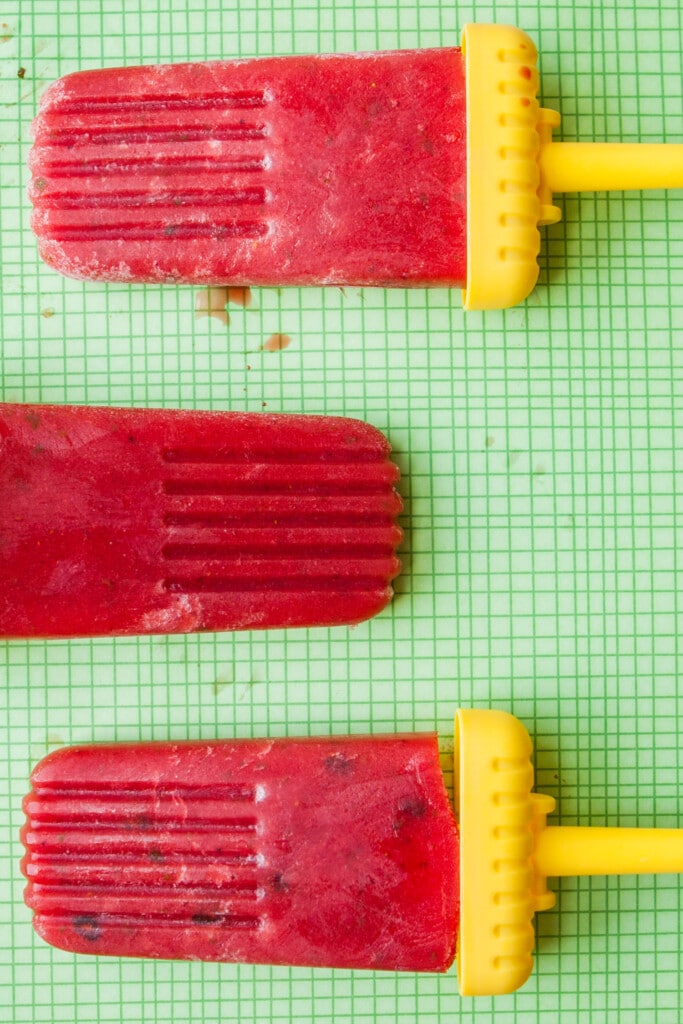 watermelon lime strawberry popsicles on green backdrop.