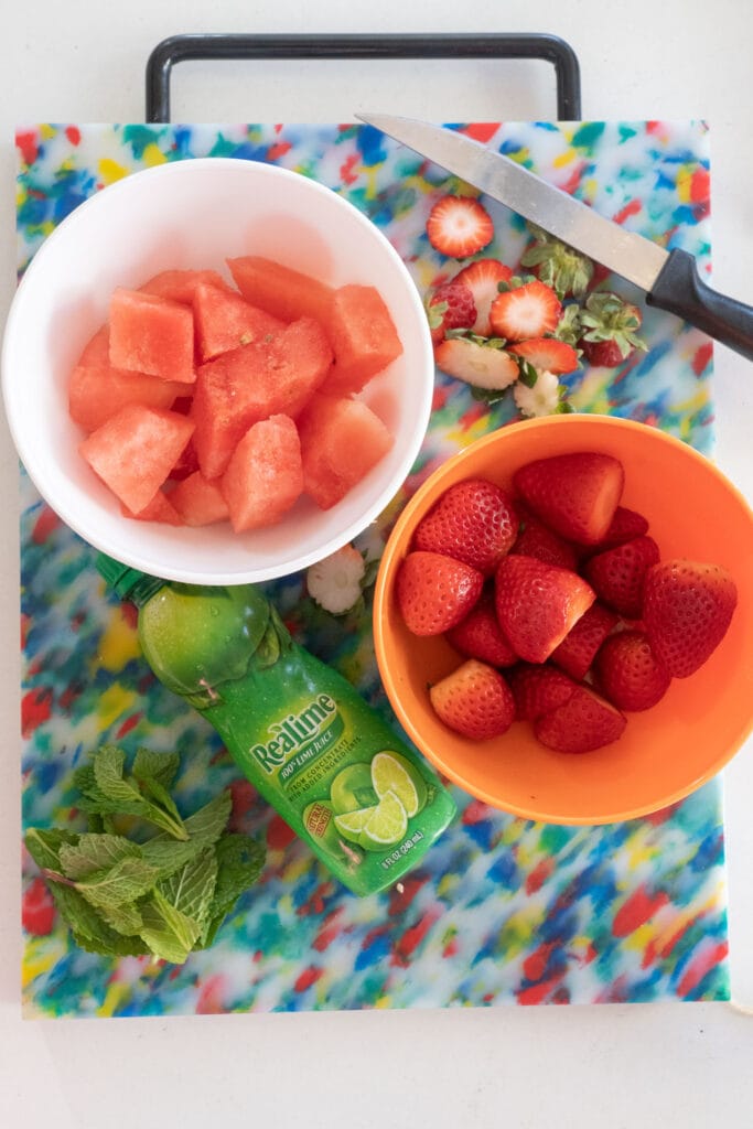 watermelon, strawberries, mint and lime on table. 