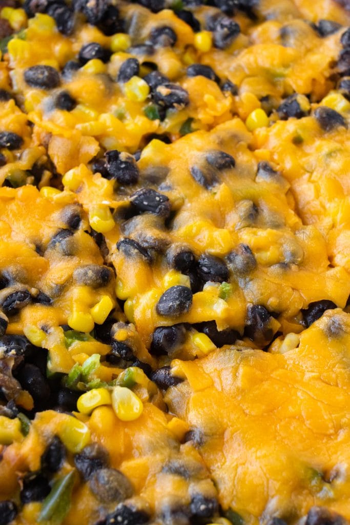 closeup of slices of enchilada casserole with cheddar cheese melted on top.
