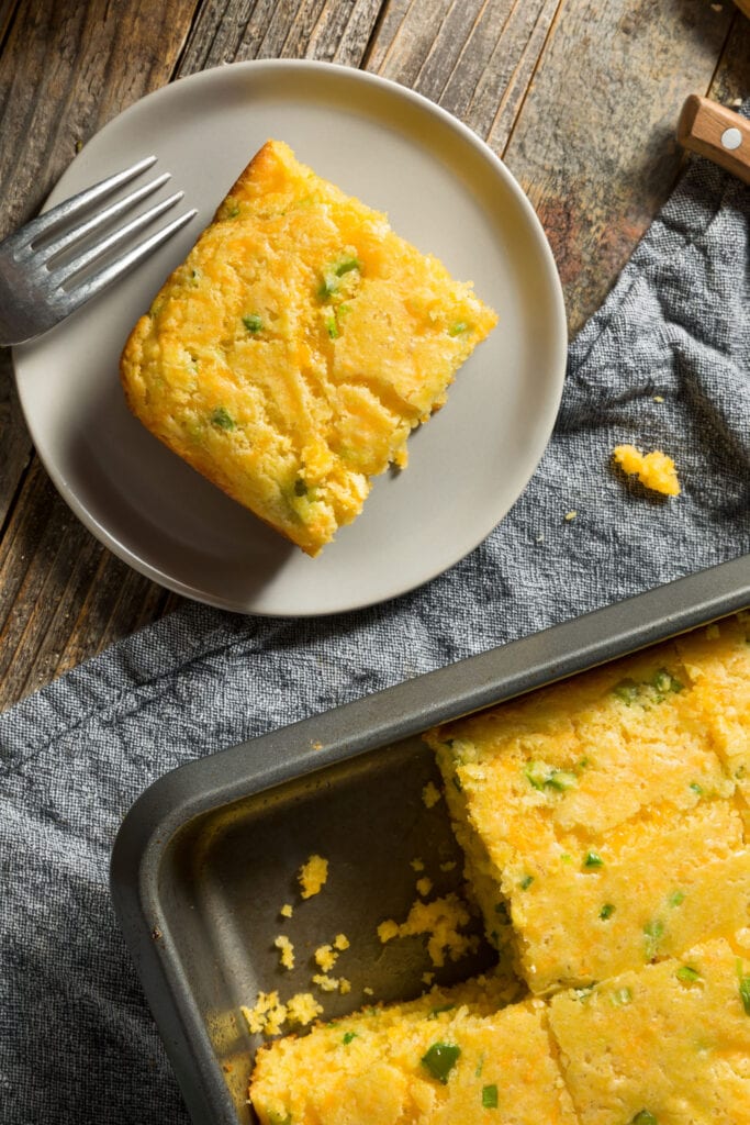 slice of cornbread removed from pan on plate with fork. 