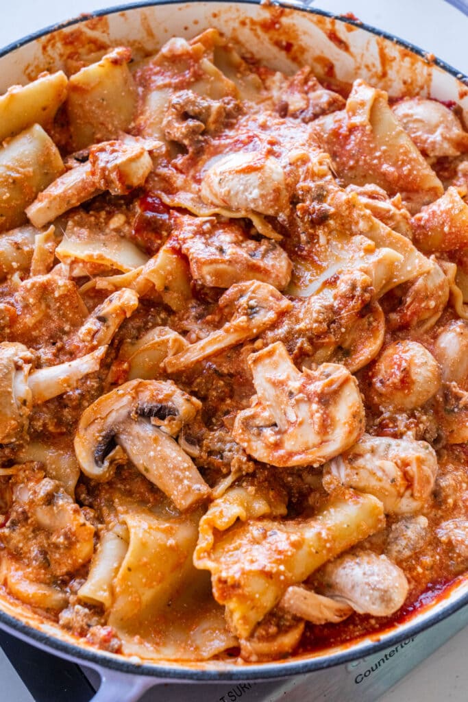 sausy lasagna with cheese and mushrooms in skillet.