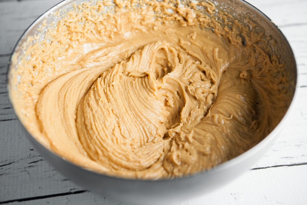 peanut butter frosting in bowl on white table.