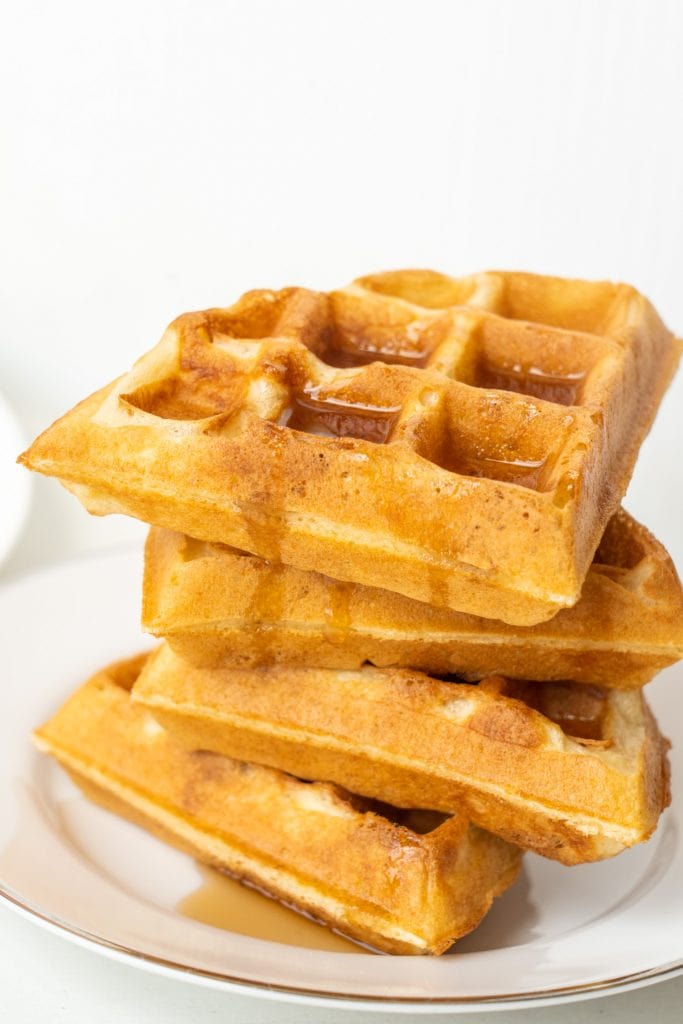 stack of waffles with syrup on them on plate.