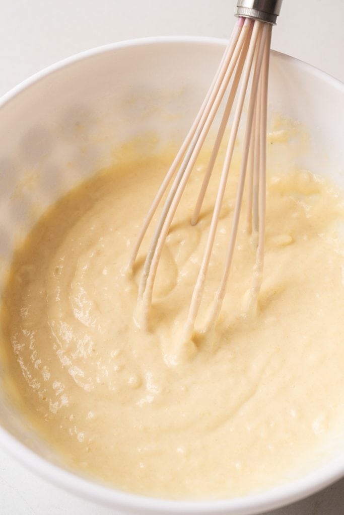 whisk making waffle batter in white bowl. 