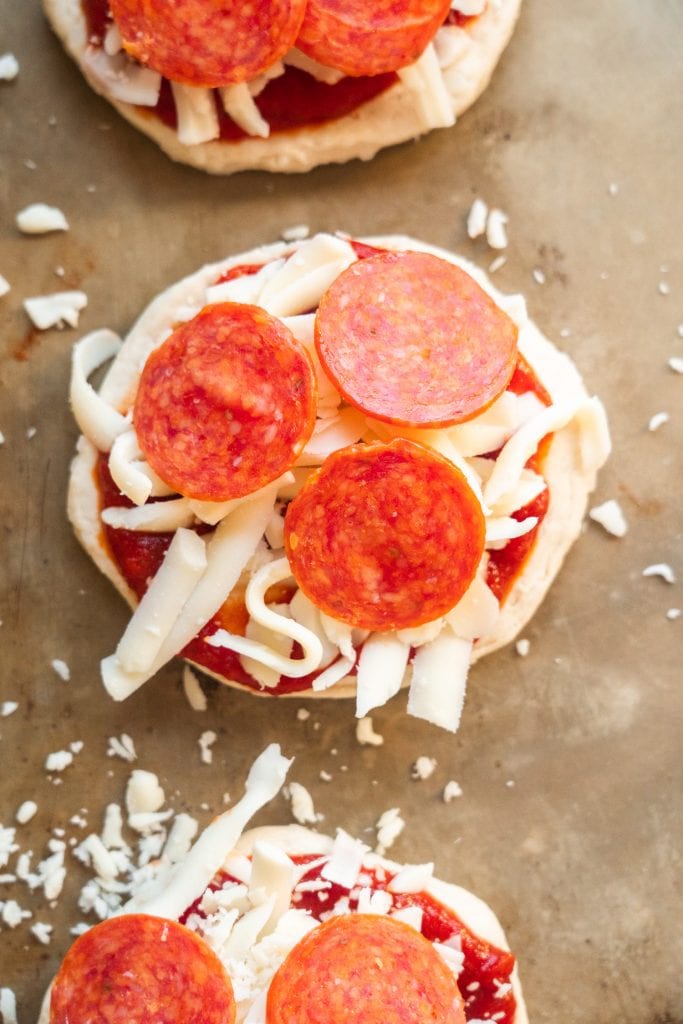 raw biscuit dough with shredded cheese and pepperonis on it.