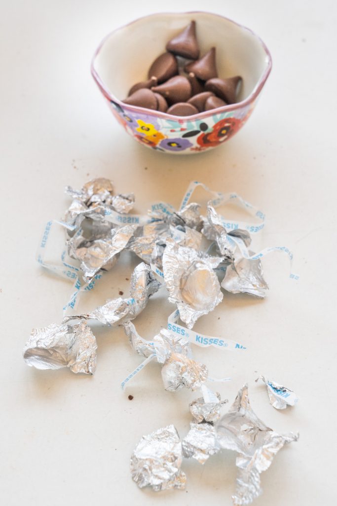 hershey kisses in bowl with wrappers next to them.