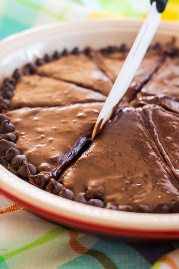 knife cutting slices of chocolate oreo pie in pie dish.