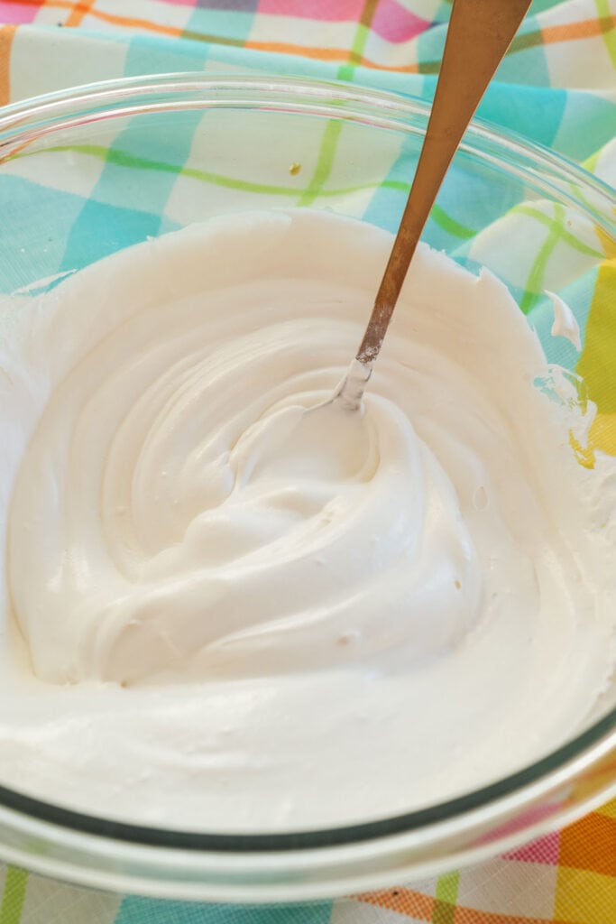 whipped cream in bowl with spoon mixing it.