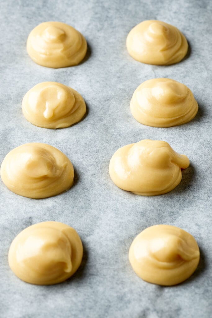 unbaked cream puffs on parchment paper. 