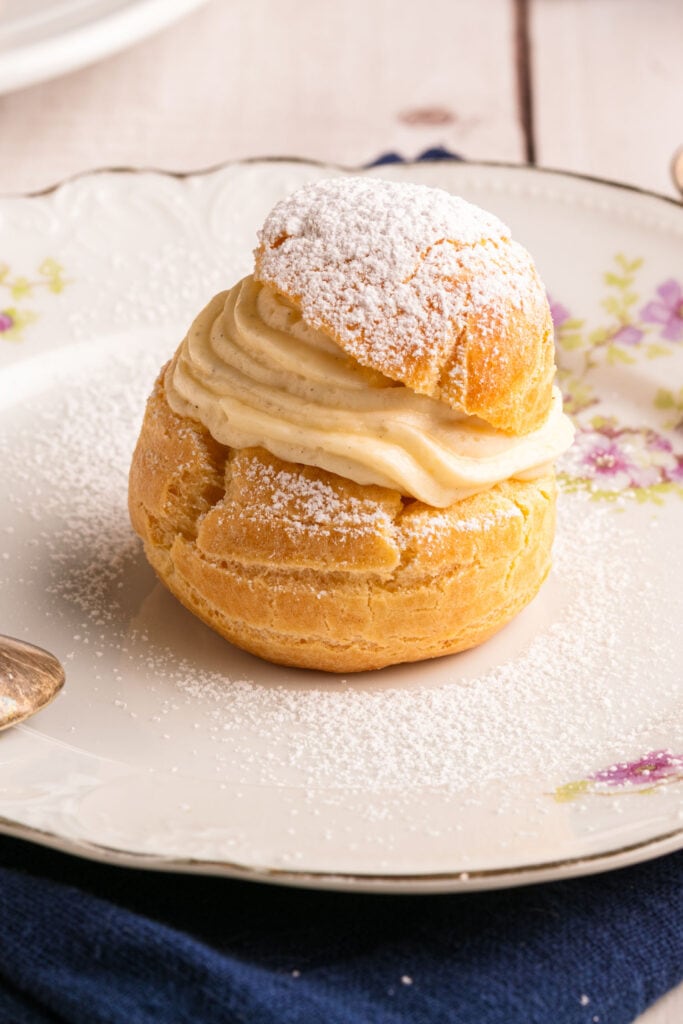 cream puff with vanilla pudding filling on top of floral plate.