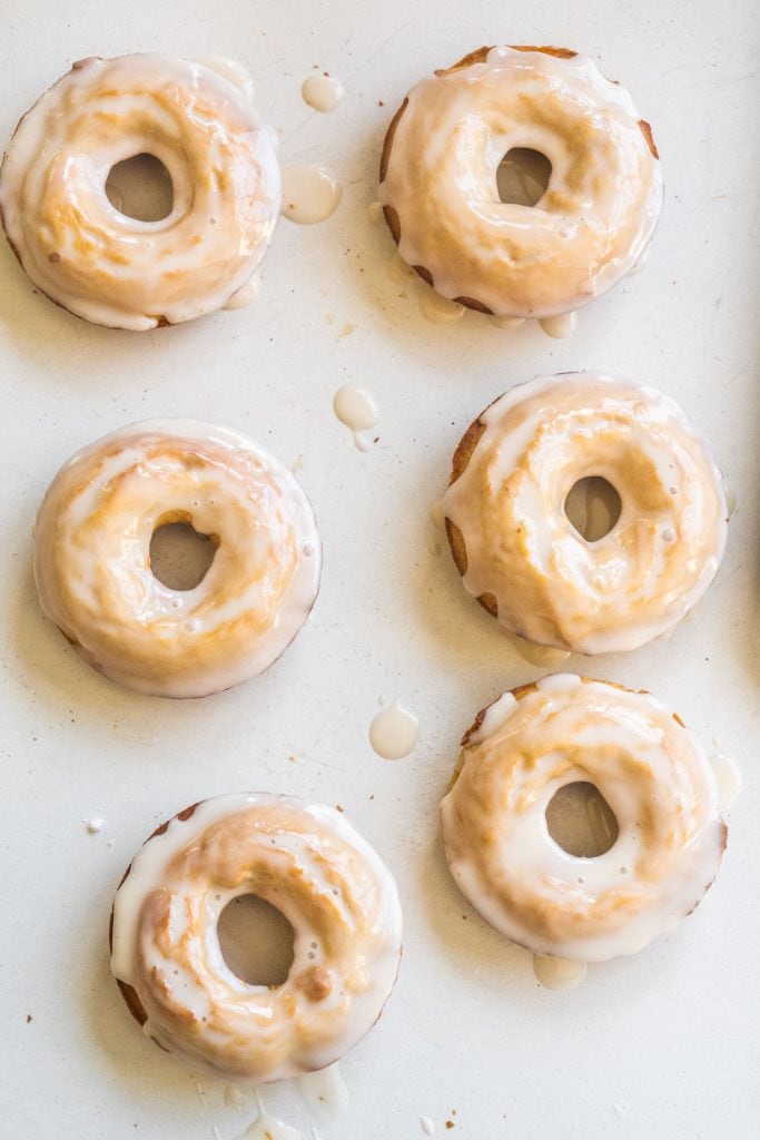 vanilla glazed donuts sitting on white table.