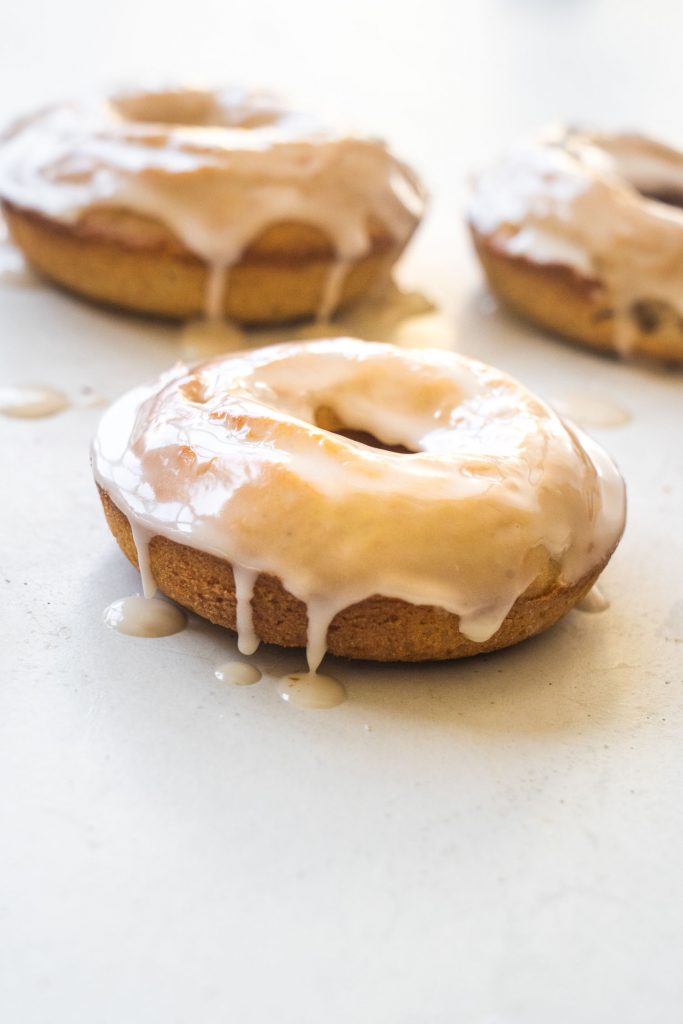 donuts on table with vanilla frosting dripping down sides.