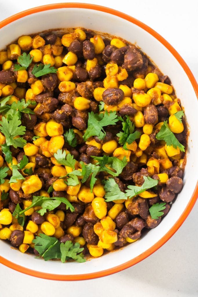 bowl filled with black bean corn salsa with chopped cilantro on top. 