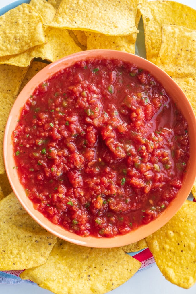 tortilla chips surrounding bowl of salsa in bowl in the middle.