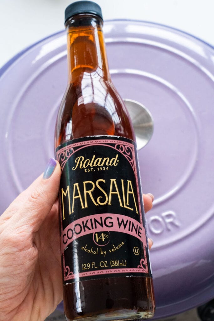 hand holding glass bottle of marsala cooking wine.