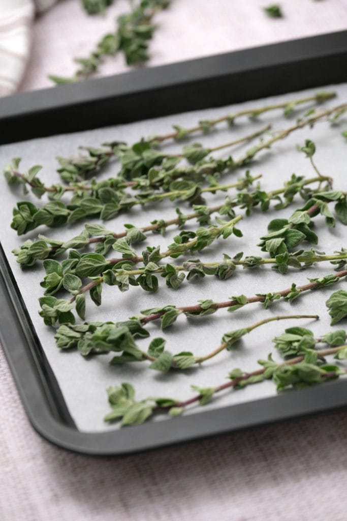 fresh oregano leaves on baking sheet on parchment paper