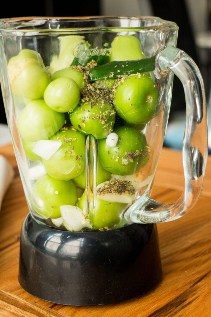tomatillos and other ingredients in blender before being blended into salsa. 