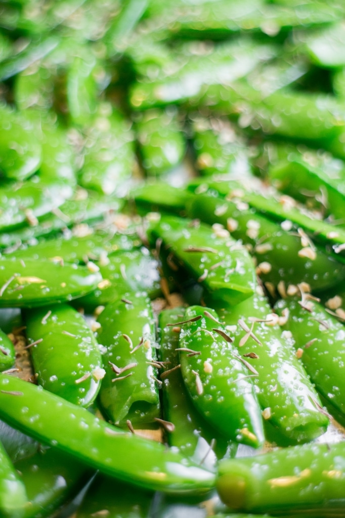Baked Sugar Snap Peas are easy to make and healthy for you! Sprinkle with garlic, thyme and salt and bake for 8 minutes.