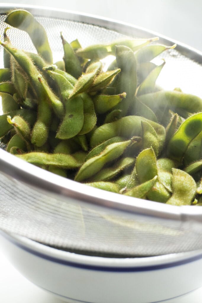 edamame in mesh strainer being cooled down