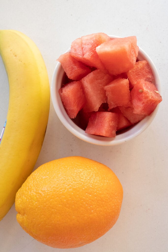 watermelon, banana and orange on table.