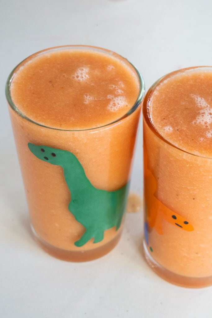 orange smoothie in dinosaur glass.