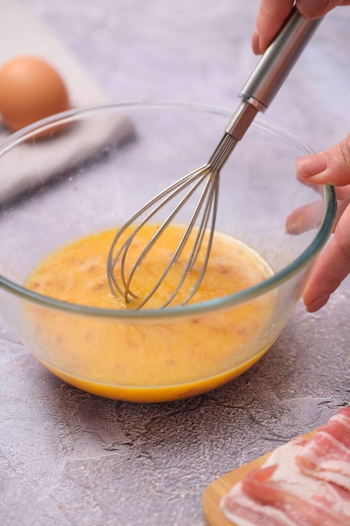 glass bowl whisking eggs and bacon