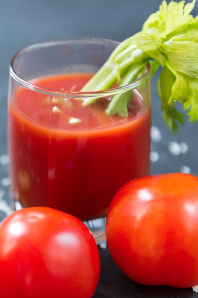 glass of tomato juice on table with fresh tomatoes.
