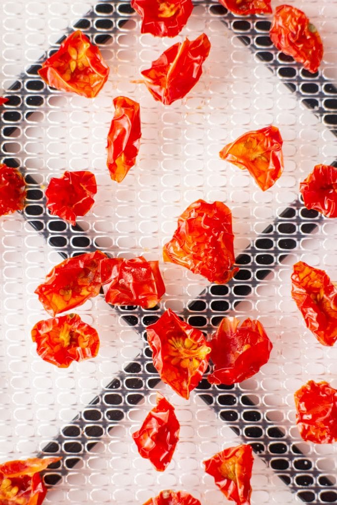 dehyrated cherry tomatoes on food dehydrator sheet.