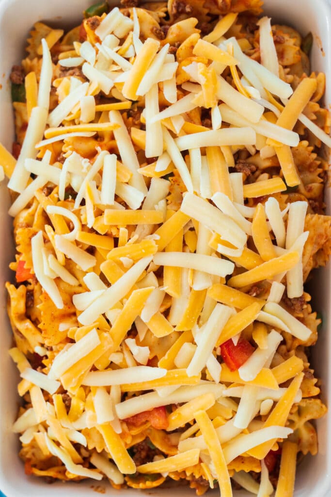 shredded cheese on top of ingredients in baking dish.