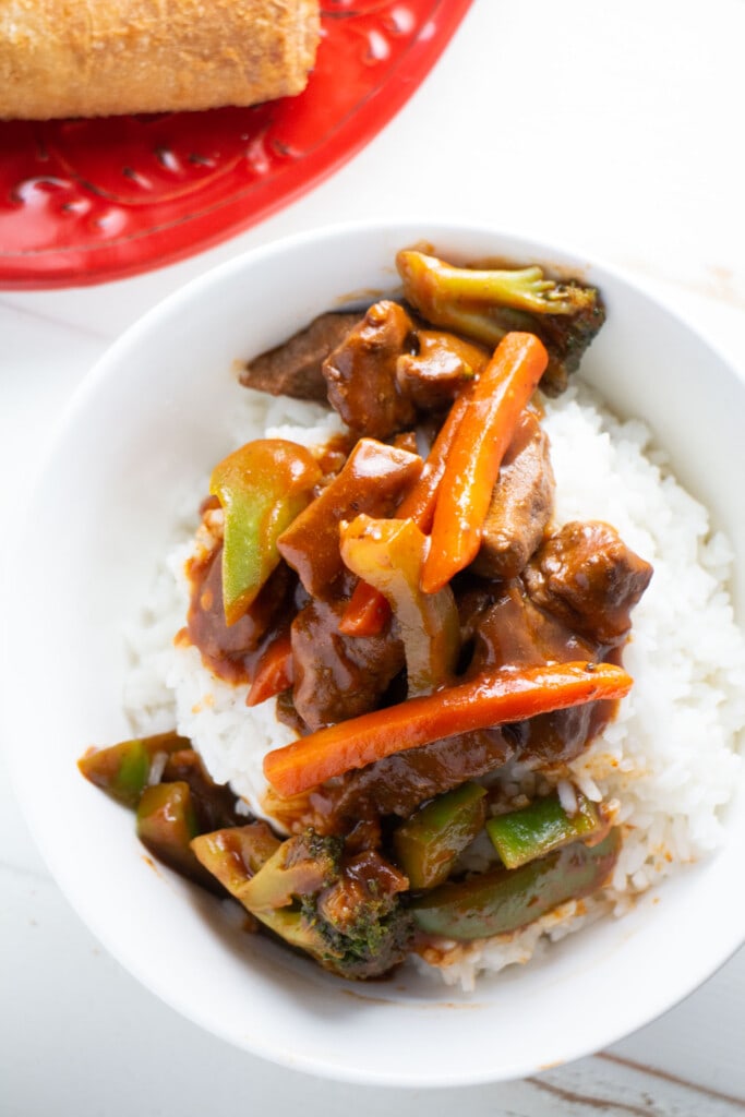 bowl of pepper beef and vegetables over rice in bowl l