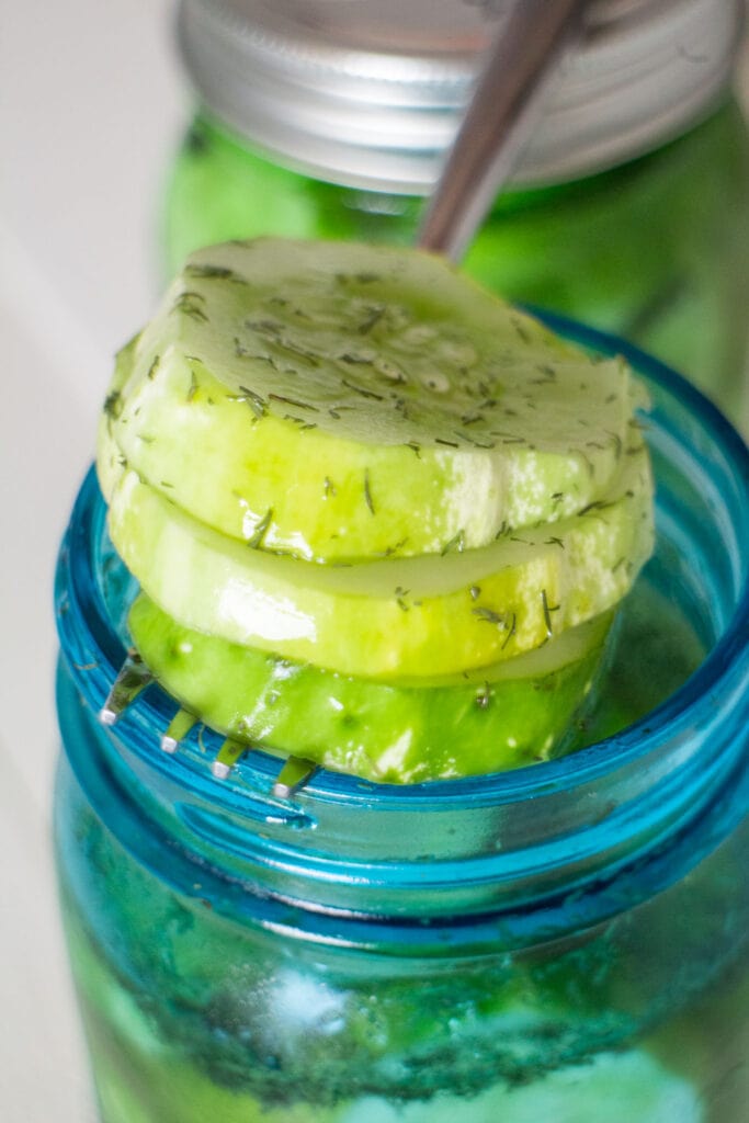 sliced dill pickles coming out of mason jar.