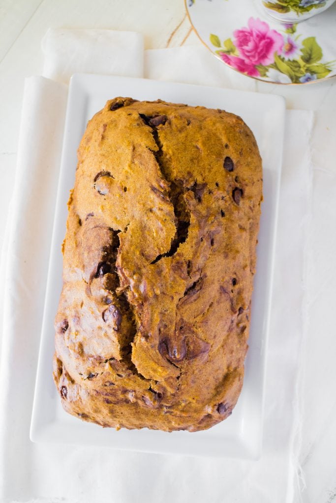 loaf of chocolate chip carrot bread on white plate.