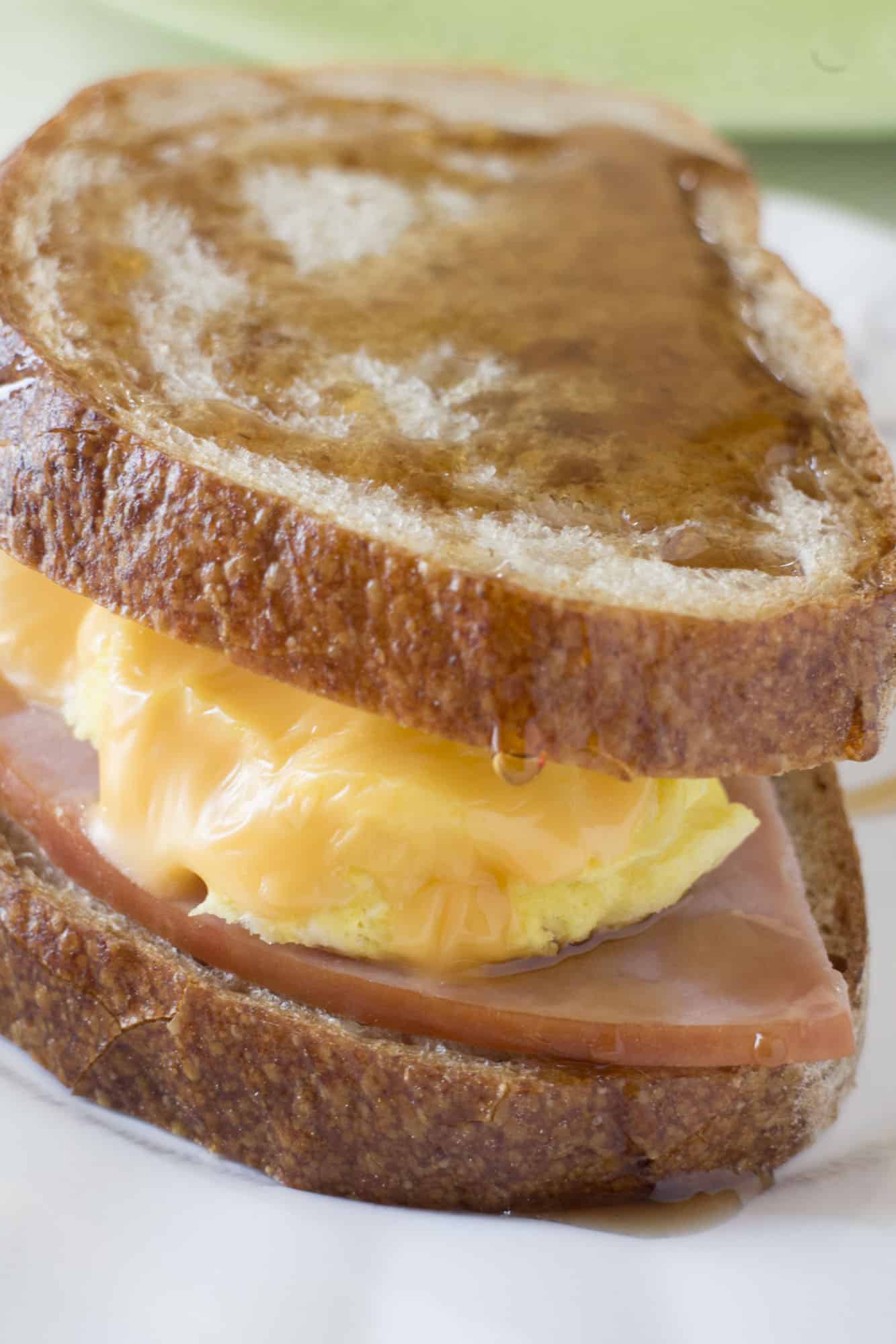EASY, YUMMY breakfast sandwich made in 2 MINUTES! This Maple Syrup, Egg, Ham and Cheese Sandwich recipe is great for a quick breakfast! You can freeze the sandwiches to make ahead too! They taste like french toast to me!