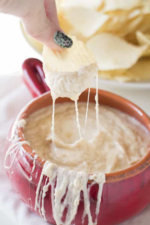 SLOW COOKER Creamy Onion Dip is so creamy and easy to make. Caramelized onions are mixed with sour cream and mozzarella cheese to make a extra creamy homemade dip! This simple recipe is best served hot with potato chips - perfect for a party dip! 