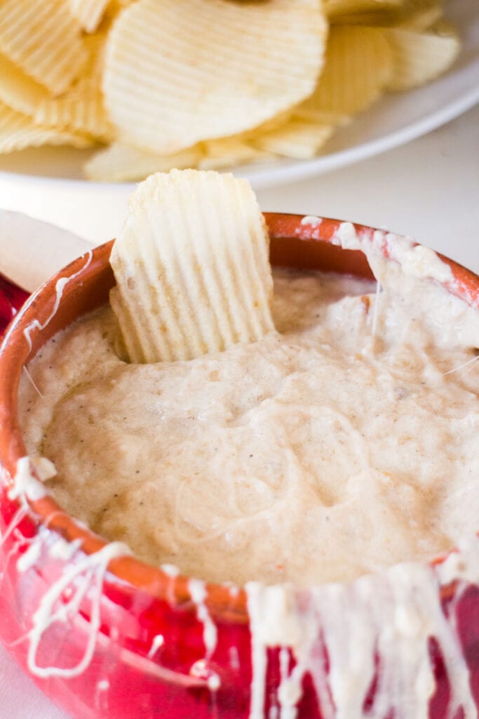 chip in onion dip in red bowl.