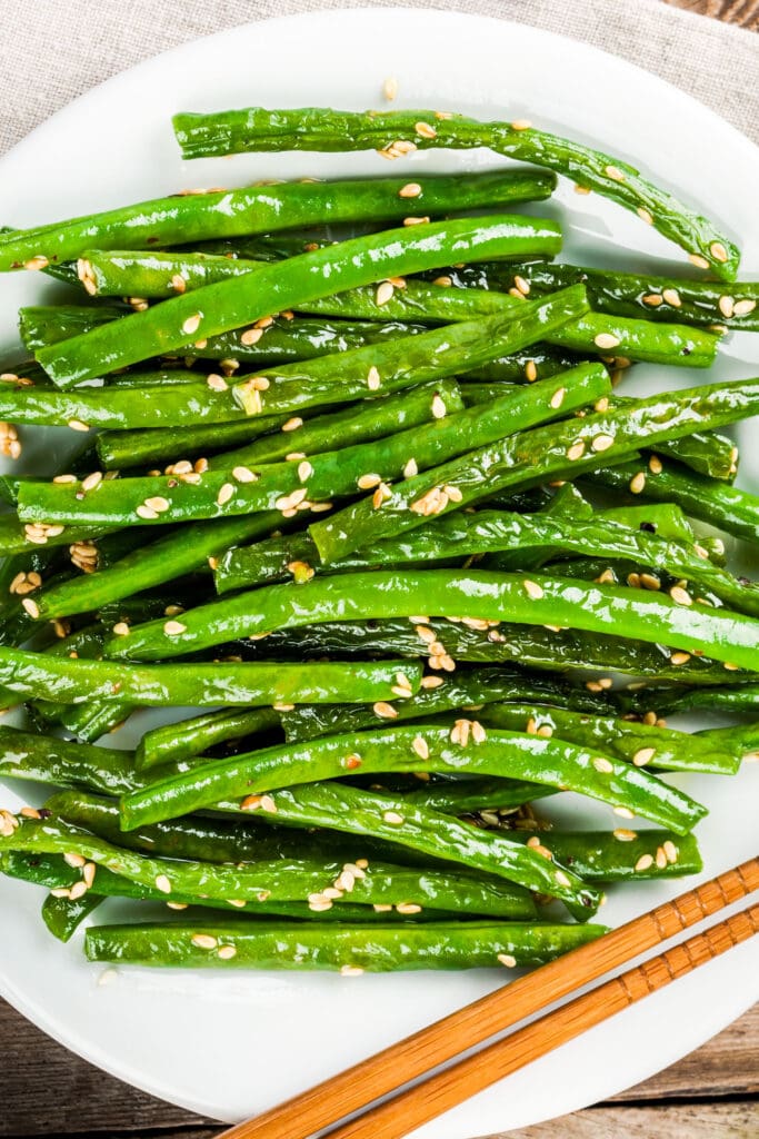 chinese green beans with sesame seeds on white plate.