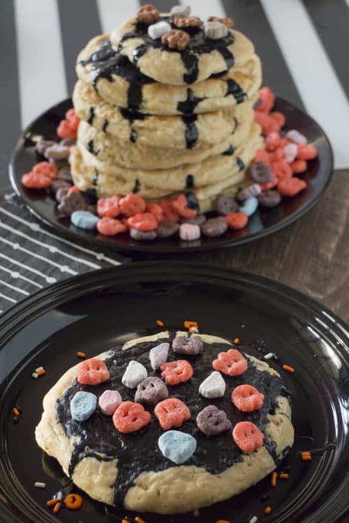 Spooky Halloween Frosted Pancakes with Count Chocula, Boo Berry and Franken Berry Cereal on top. They're perfect for a fun holiday breakfast!