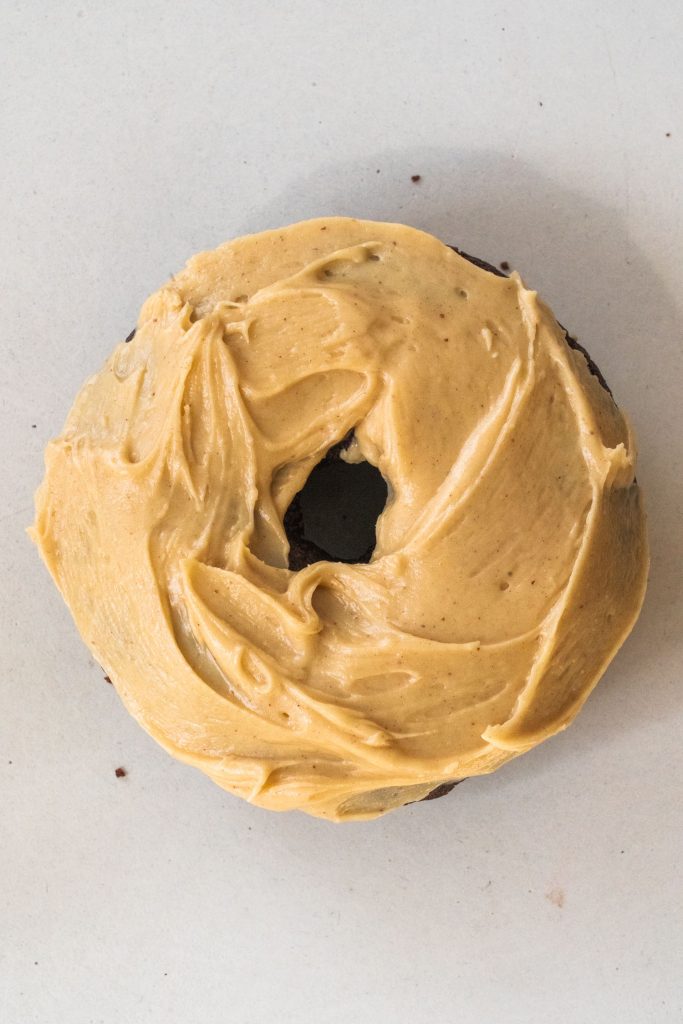single chocolate donut with peanut butter frosting on table.