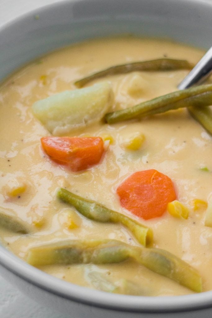cheesy soup in bowl filled with vegetables and cream soup.
