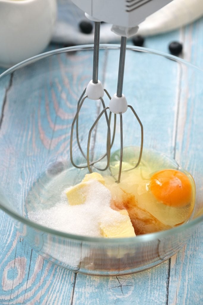 hand mixer in bowl with ingredients on blue table