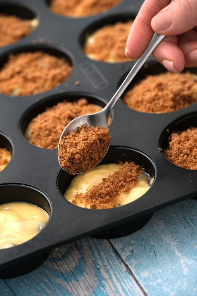 streusel crumble on spoon being sprinkled on top of muffins